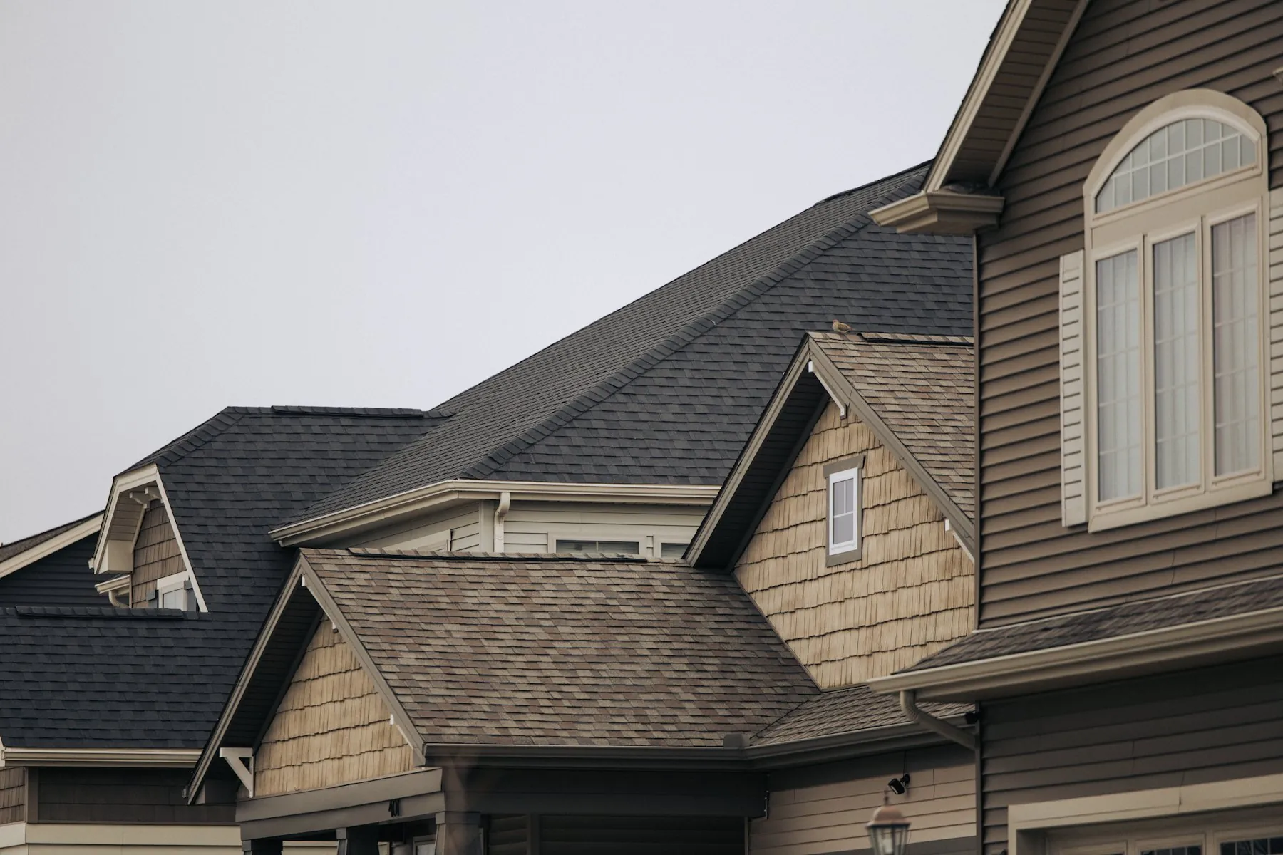 A row of houses with gray and brown shingle roofs under an overcast sky
